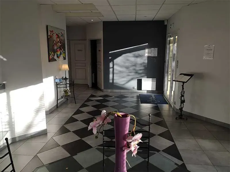 Vaste hall d'entrée avec sol en damier et éclairage naturel.